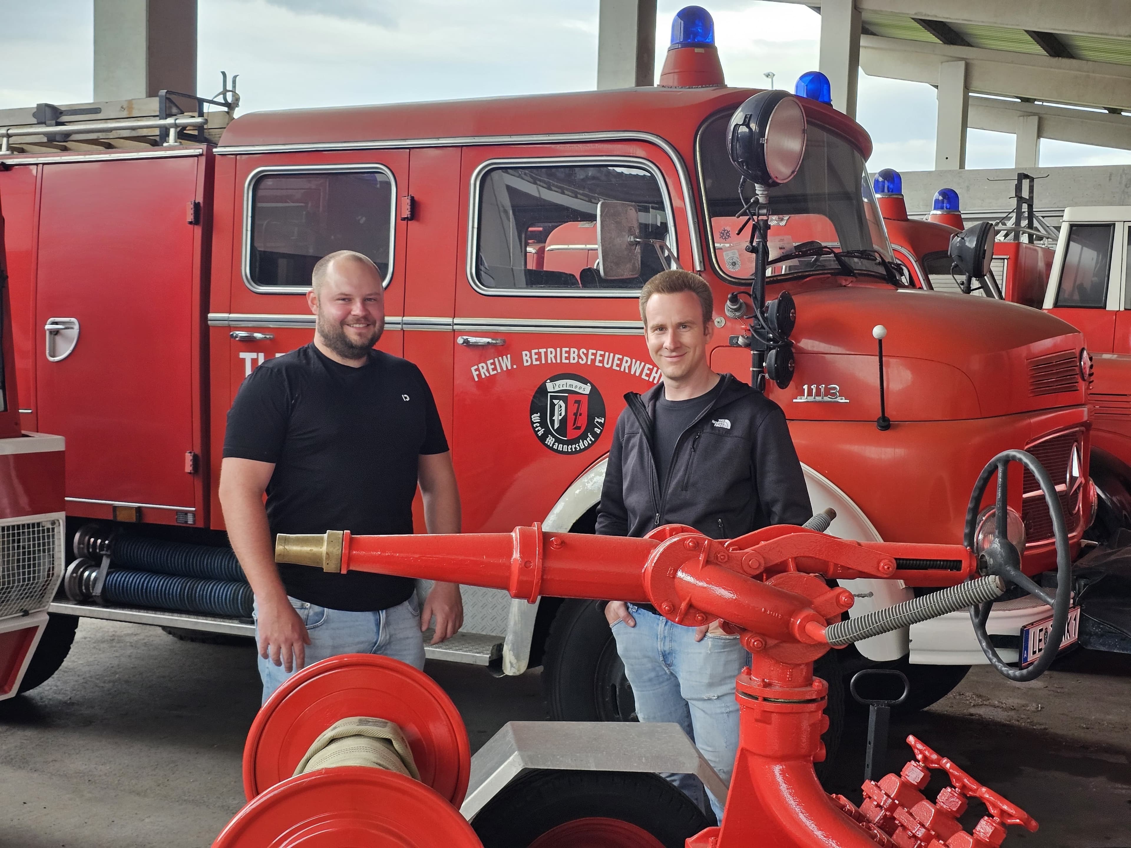 Obmann und Stellvertreter der Roten Flitzer vor einem historischen Feuerwehrfahrzeug